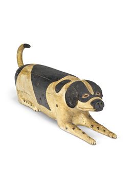 A CARVED AND PAINT-DECORATED WOOD RECLINING DOG