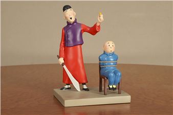 A figurine of a man holding a knife next to a man sitting on a chair.
