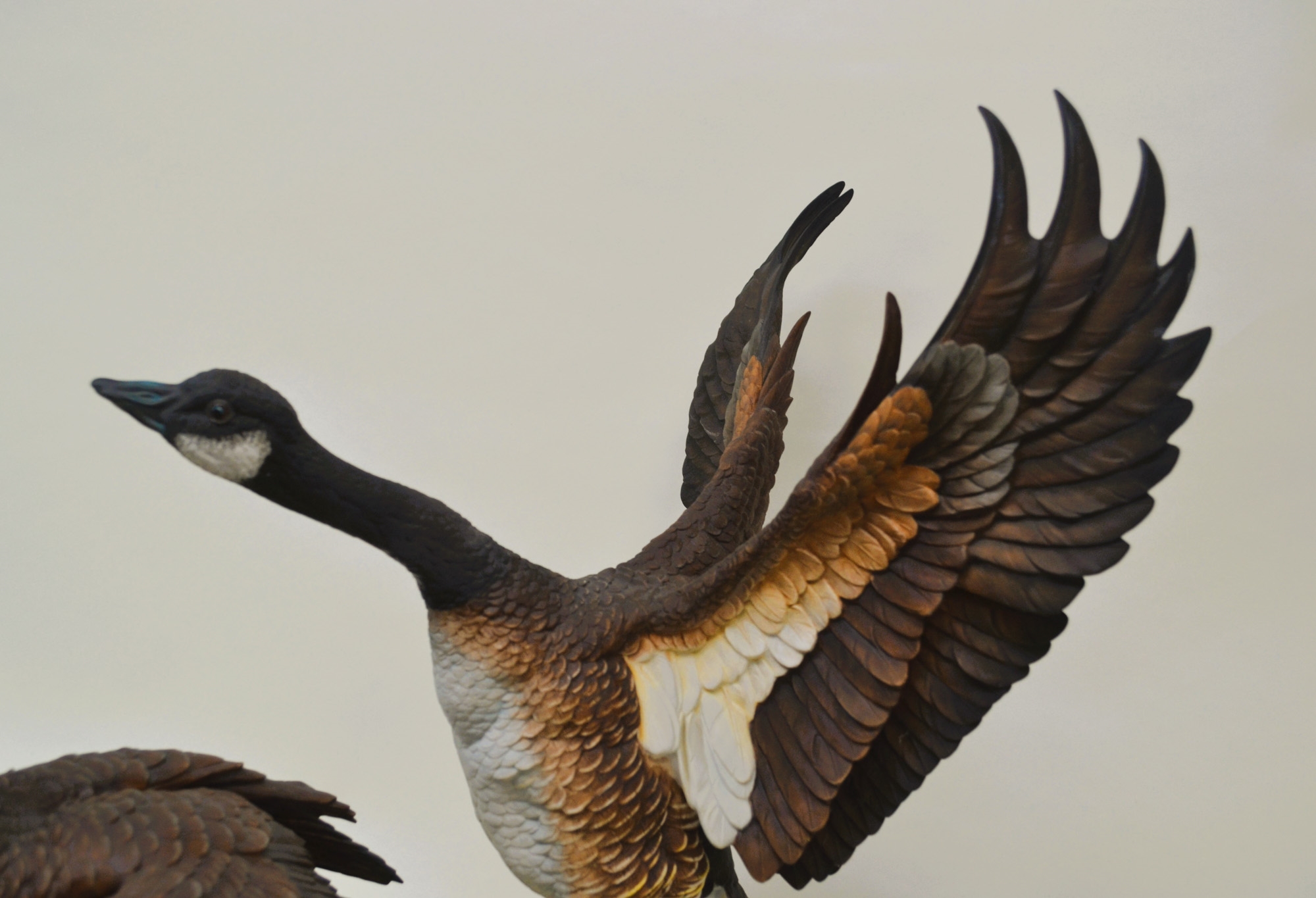 A sculptural diorama featuring two geese in flight and standing poses on a lily pad base.