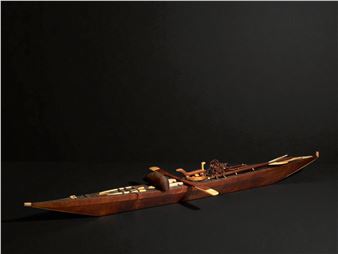 A detailed wooden rowing boat model with intricate inlay work, set against a dark background.