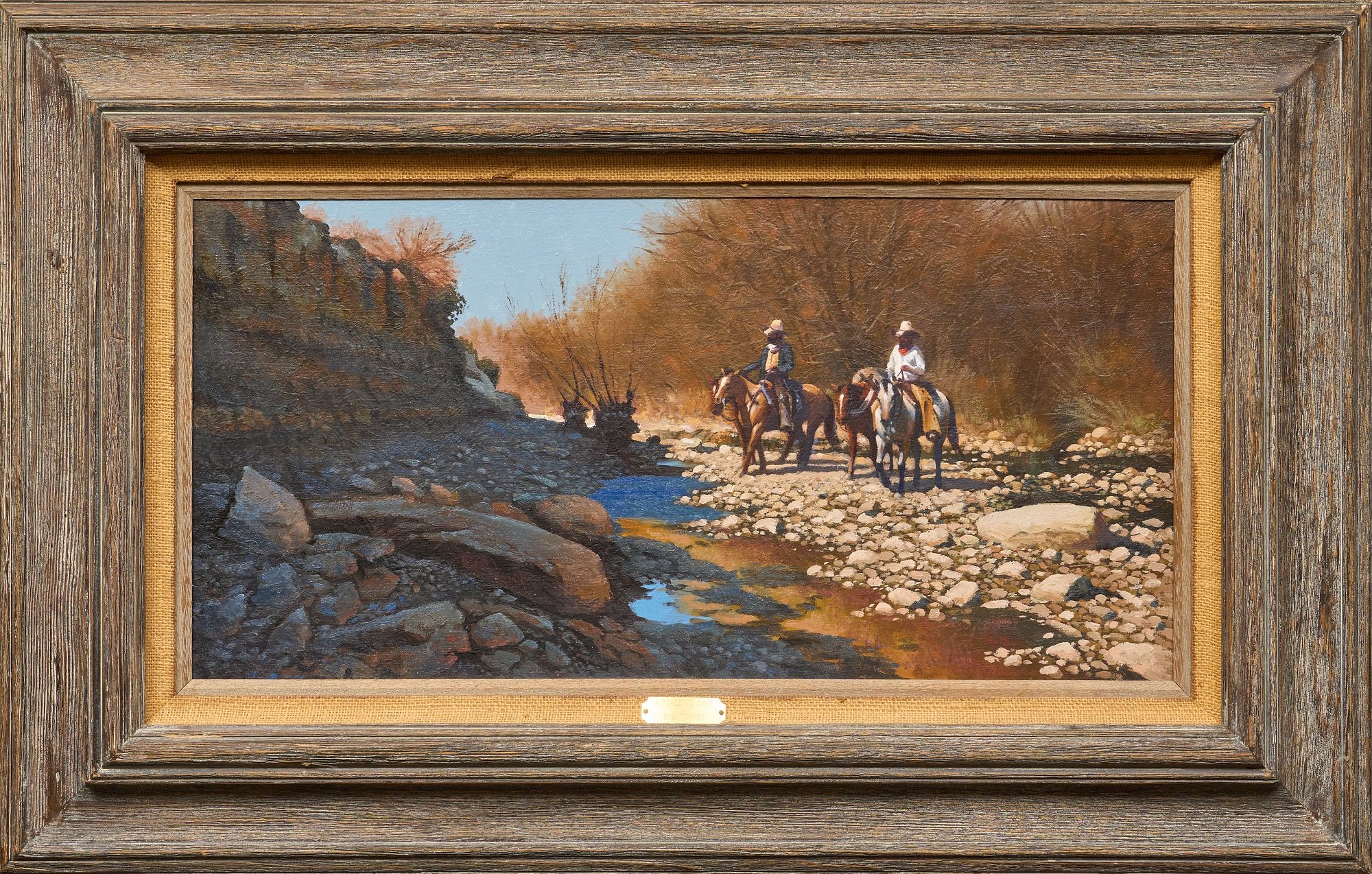 A tranquil landscape painting featuring two figures on horseback traversing a rocky riverbed.