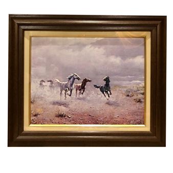 A framed painting of wild horses galloping across a dusty plain under a cloudy sky.