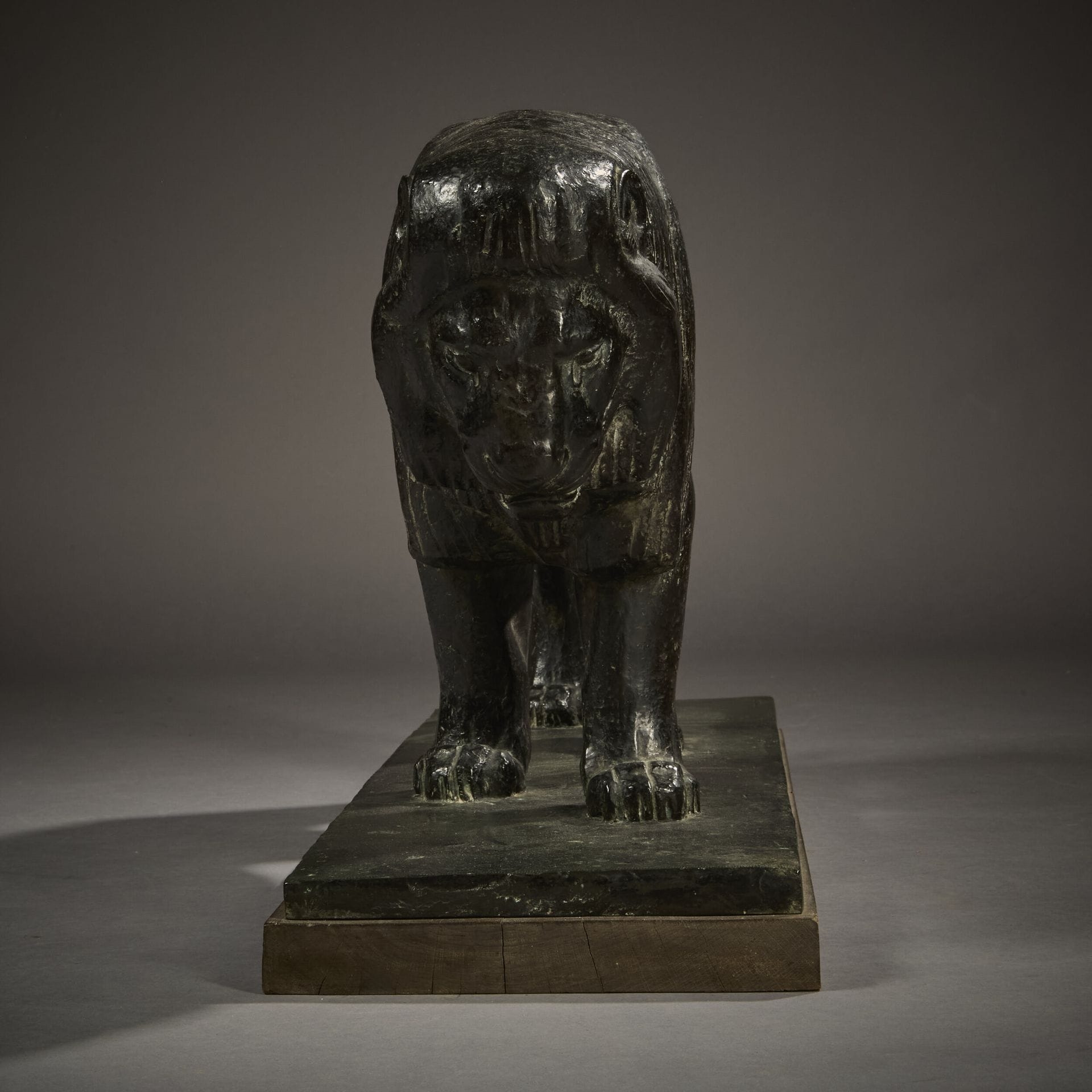 A bronze sculpture of a lion on a wooden base.