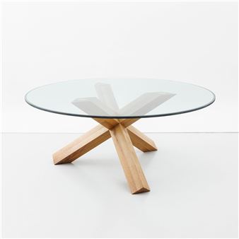 A round glass table with a wooden base and a glass top.