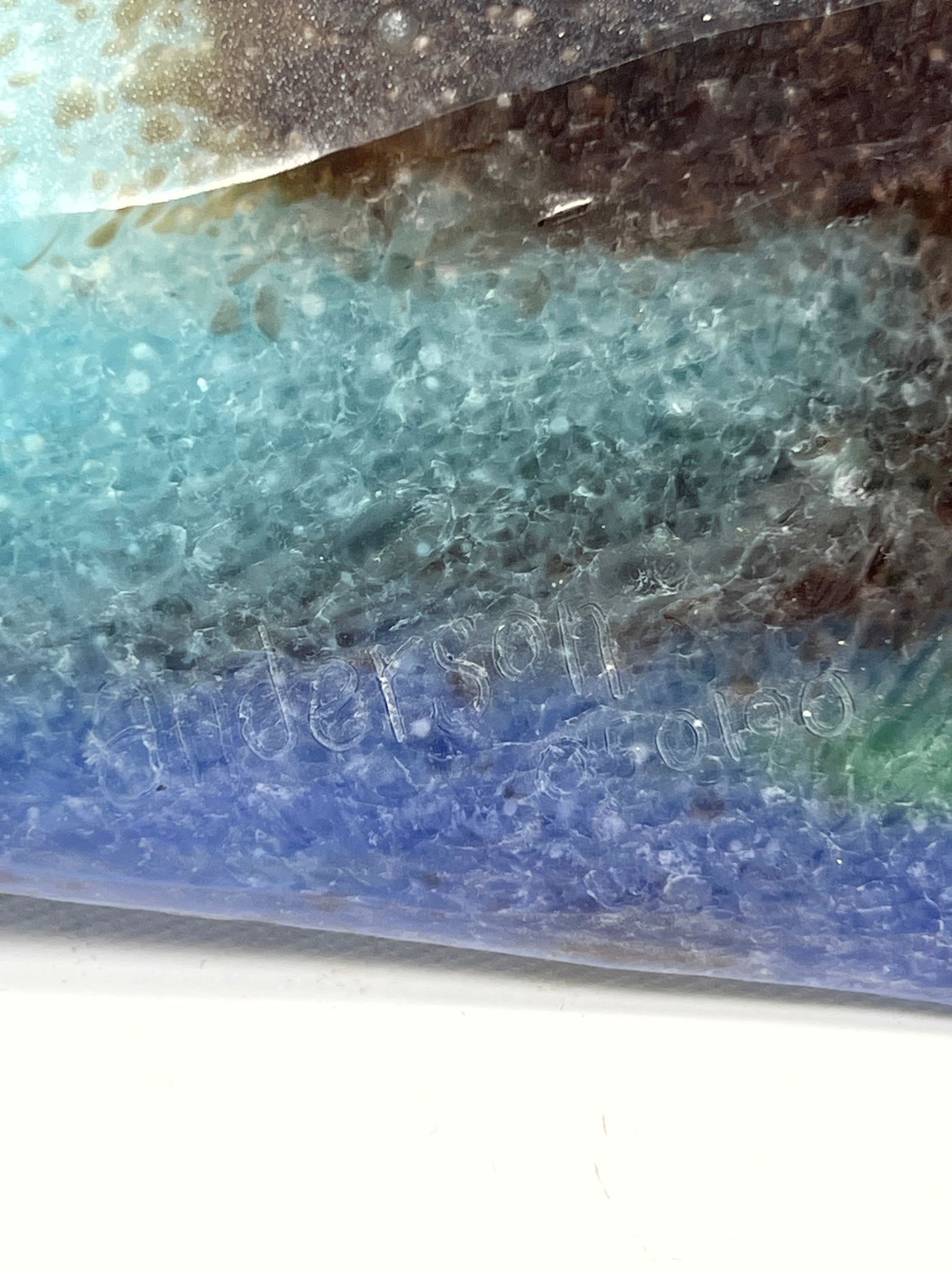 A vertical mixed-media artwork featuring tall green blades and scattered safety pins against a blue gradient background.