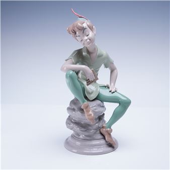 A whimsical ceramic figurine of a seated figure with a red horn, posed on a rocky base.