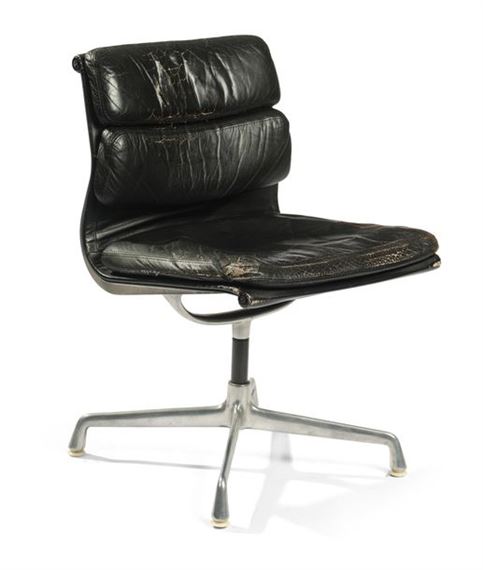 A worn black leather lounge chair with a chrome base.