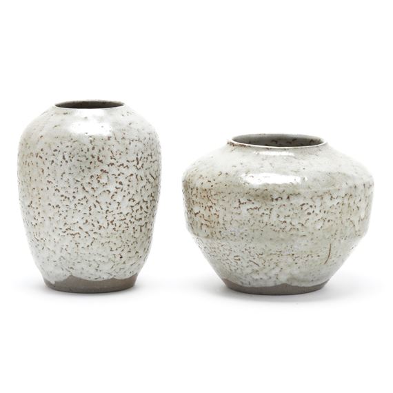 A pair of speckled ceramic vases with a rustic, handcrafted aesthetic.