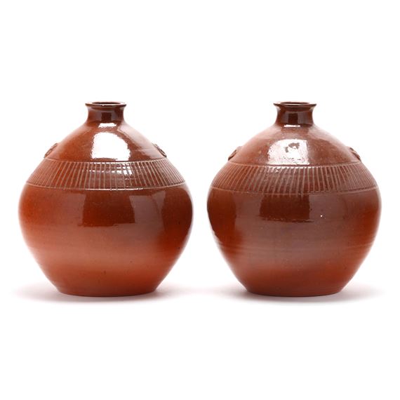 A pair of glossy brown ceramic vessels with ribbed detailing and small side handles.