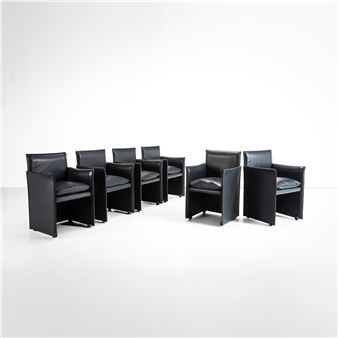 A set of six black leather chairs sitting on top of a white floor.