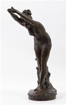 A bronze sculpture of a figure stretching with arms raised, standing on a rocky base.