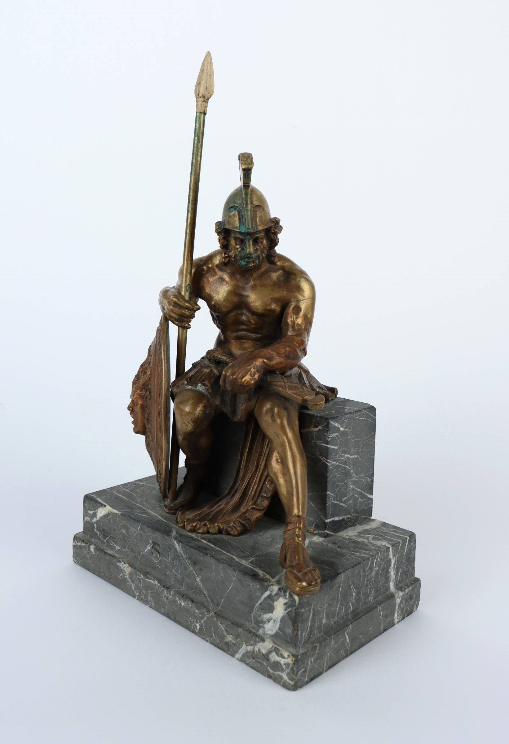 A bronze statue of a man holding a spear and shield.