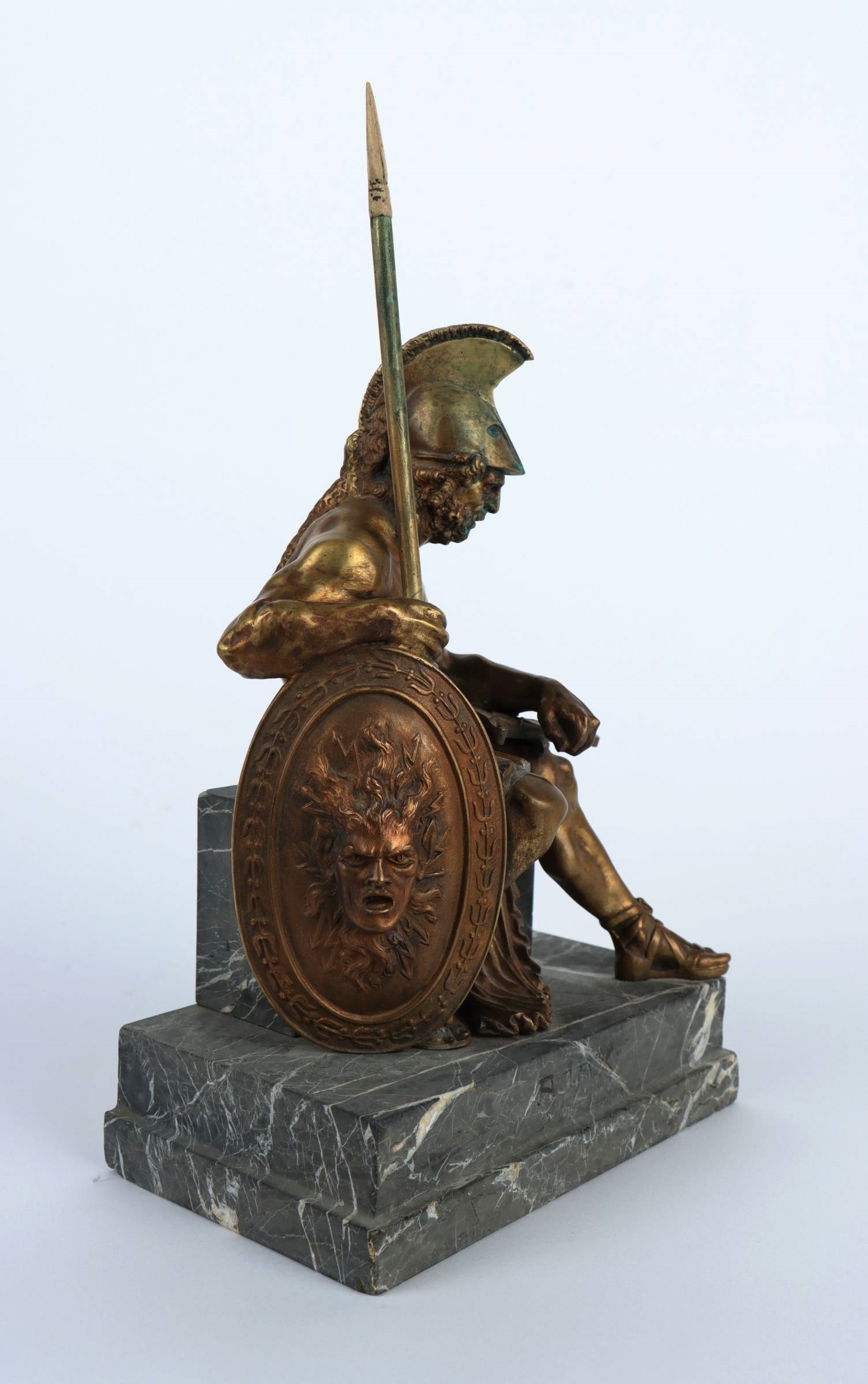 A bronze statue of a man holding a spear and shield.