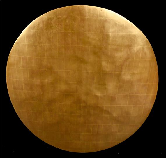 A golden circular object with a grid pattern against a black background.
