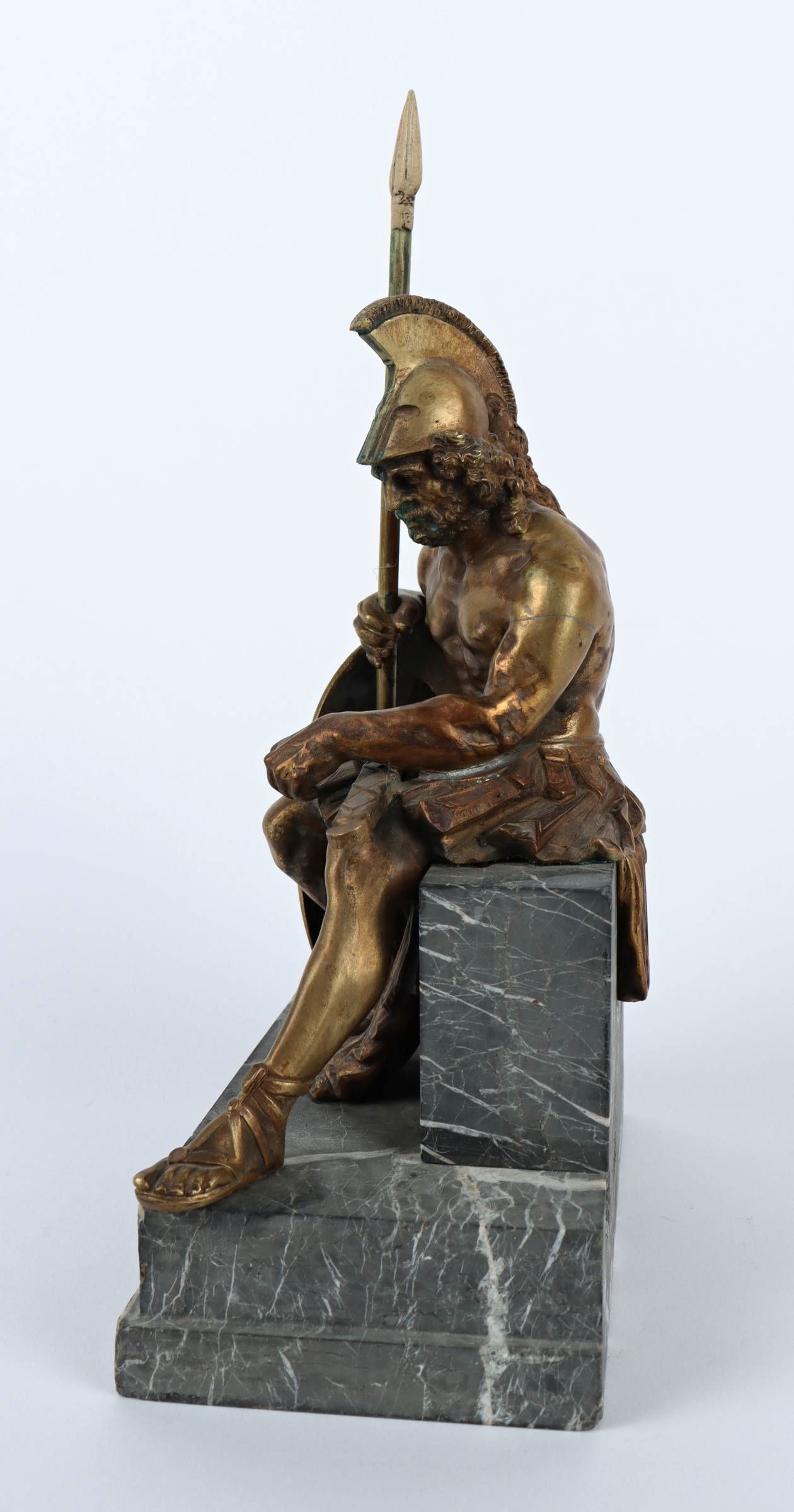 A bronze statue of a man holding a spear and shield.