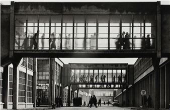 A black and white photo of people walking through a building.