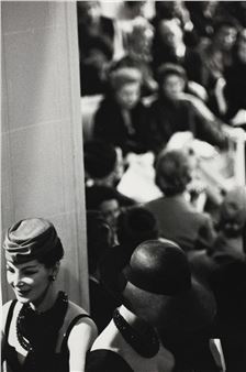 A black and white photo of a woman in a dress and hat.