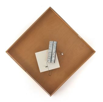 A minimalist wooden tray holds a small, abstract geometric sculpture.