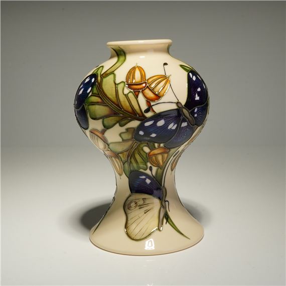 A ceramic vase featuring a botanical design with butterflies and acorns.