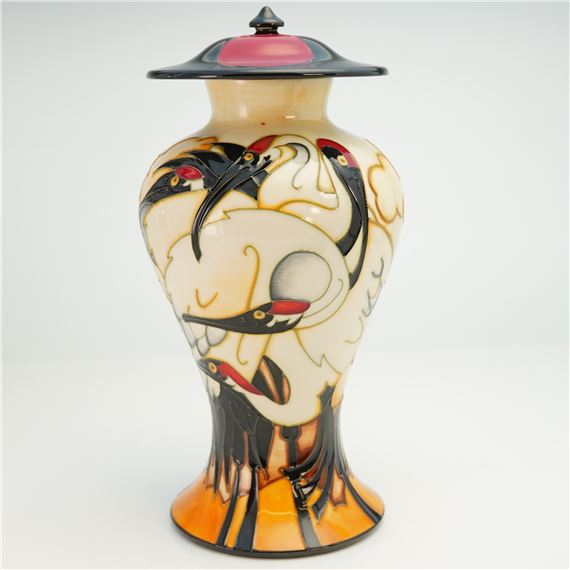 A ceramic lidded vase featuring stylized bird figures in black, red, and cream against a white background.