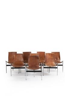 A group of six brown leather chairs arranged in a circle against a stark white background.