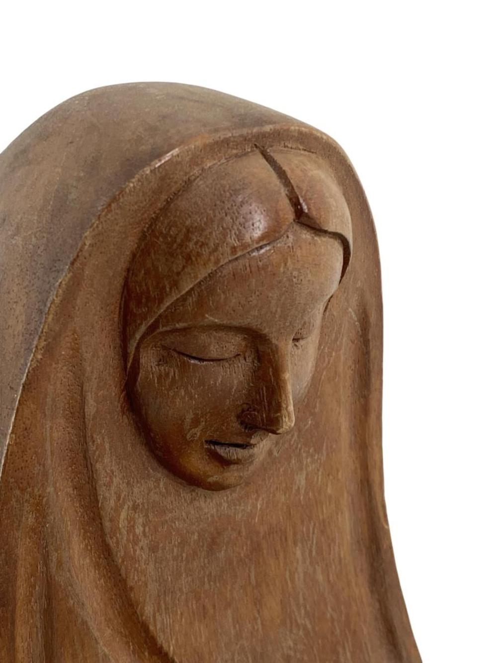 A wooden sculpture of a seated figure cradling a small head.
