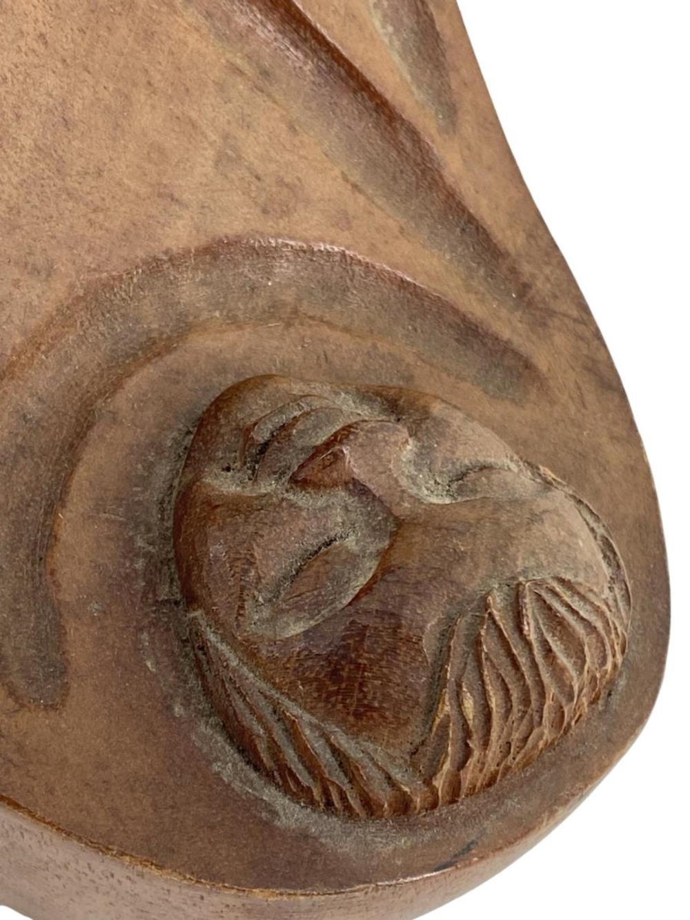 A wooden sculpture of a seated figure cradling a small head.