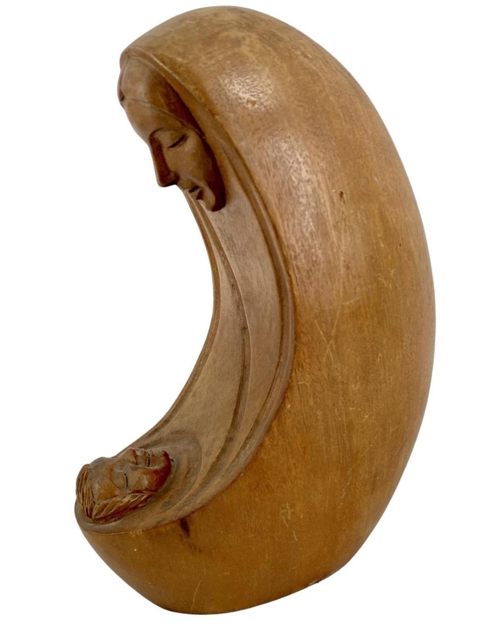A wooden sculpture of a seated figure cradling a small head.