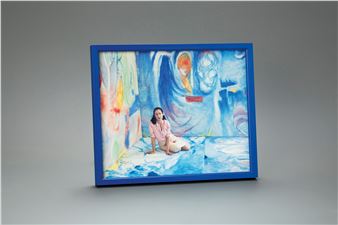 A blue-framed artwork featuring a person sitting amidst swirling abstract colors.
