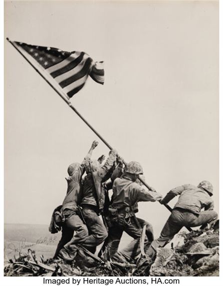 A group of men raising a flag on top of a mountain.