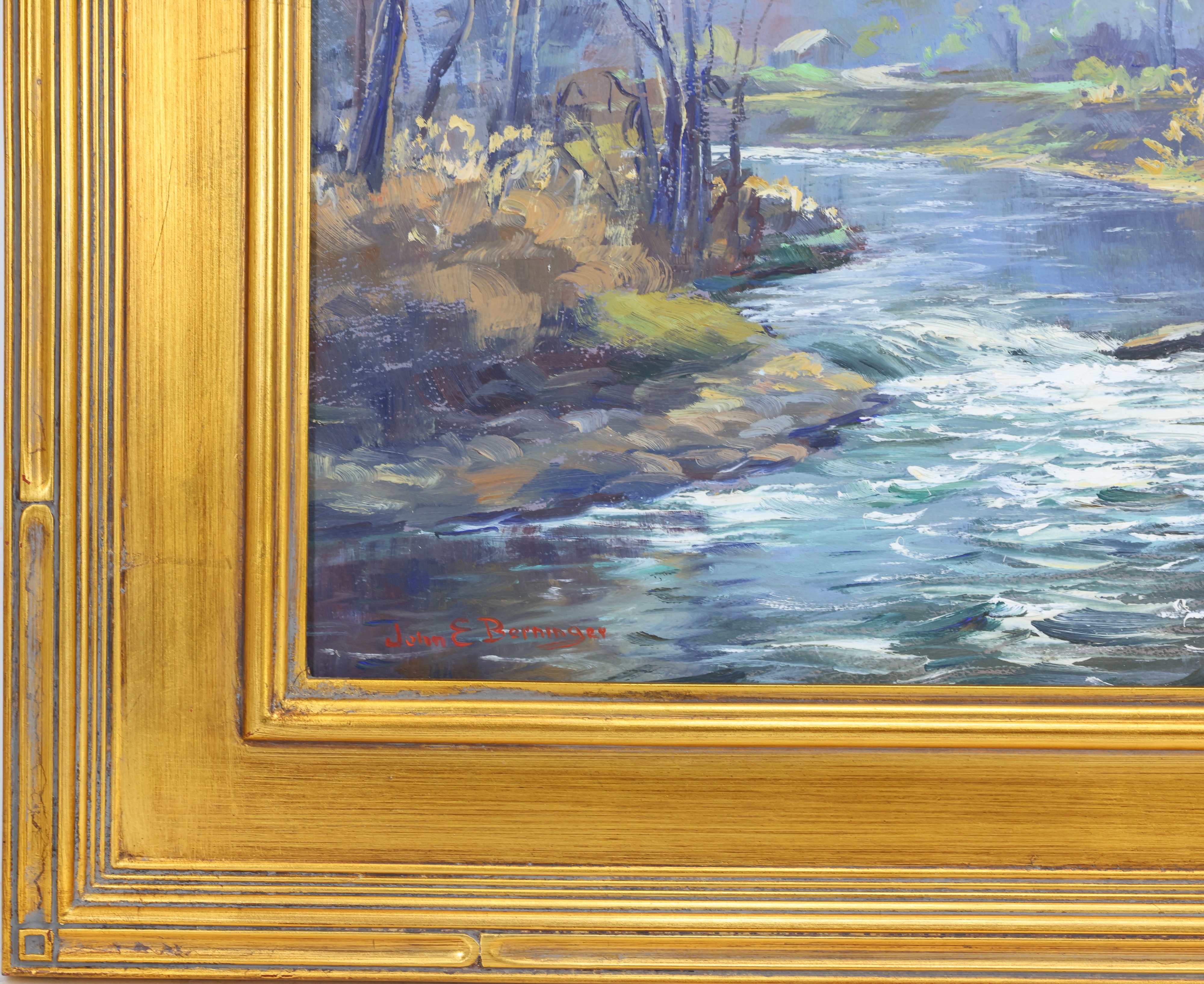 A serene landscape painting of a river flowing through a wooded valley, framed in ornate gold.