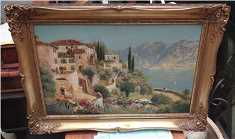 A framed painting of a sun-drenched lakeside village with terracotta roofs, cypress trees, and distant mountains.