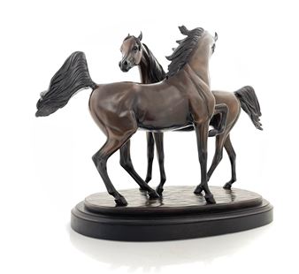 A bronze sculpture of two horses standing side by side on a wooden base.