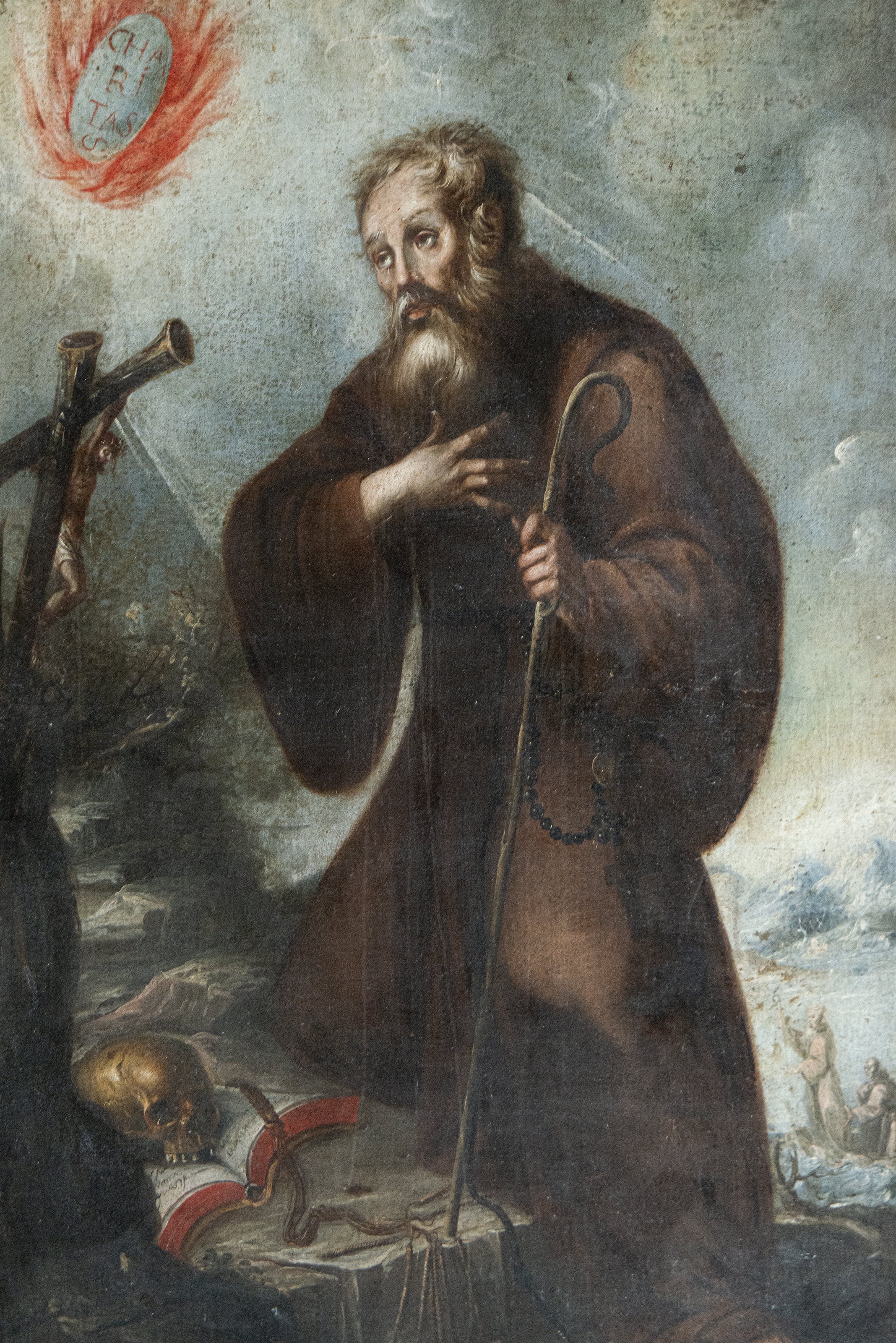 A solemn religious portrait of a bearded figure in dark robes holding a staff, set against a dramatic cloudy sky.