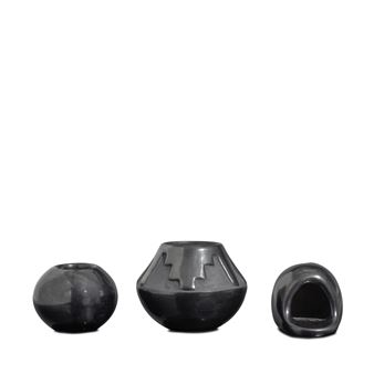 A minimalist display of three black ceramic objects arranged in a row against a stark white background.