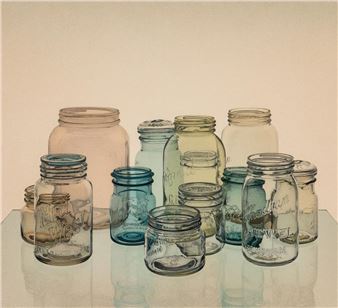 A collection of glass jars in varying sizes and tints arranged on a reflective surface.