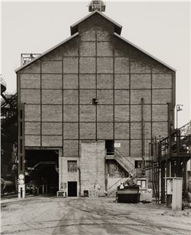 A monochrome architectural study of a large brick industrial building.