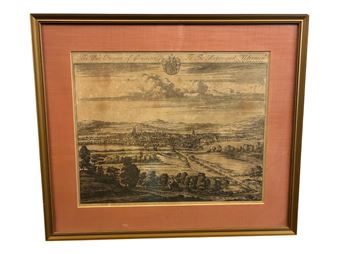 A framed etching of a historic town landscape with detailed architectural and natural elements.