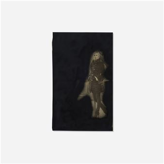 A monochromatic portrait of a figure standing against a dark background.