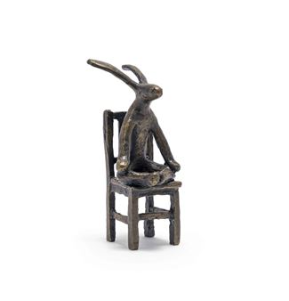 A bronze sculpture of a rabbit sitting on a chair.