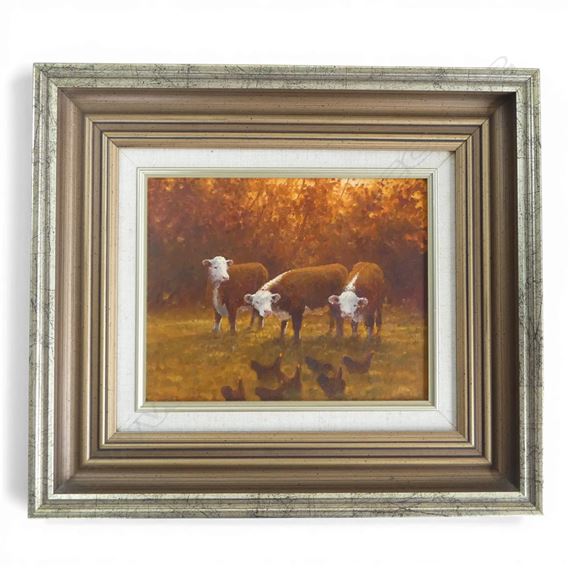 A framed pastoral painting of cattle in a golden field with chickens below.