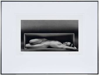 A monochrome print of a nude figure resting inside a rectangular box.
