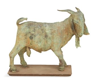 A weathered bronze sculpture of a goat standing on a rectangular base.