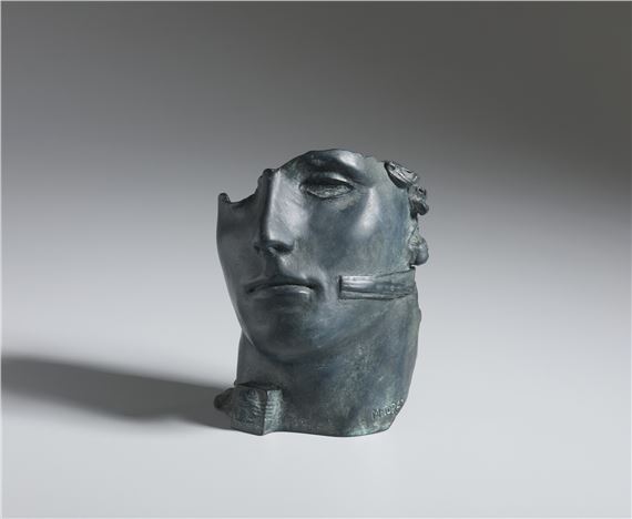 A bronze bust of a face with a jagged, broken left side.