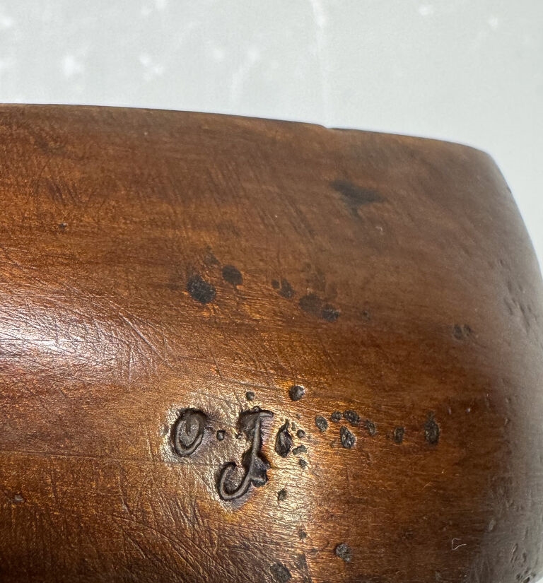 A wooden sculpture featuring a small bird perched on an irregular, boat-shaped base.