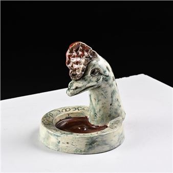 A ceramic sculpture of a bird head emerging from a shallow bowl with textured glaze.