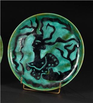 A ceramic plate featuring a stylized black tree design on a turquoise background.