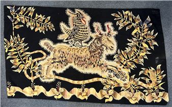 A black textile featuring a golden deer and bird surrounded by foliage.