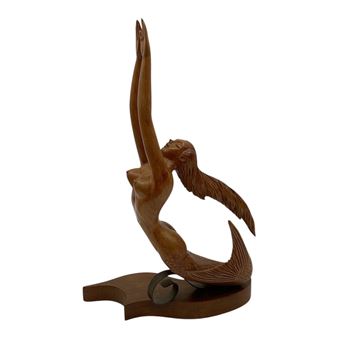A wooden sculpture of a winged figure with an upward-reaching arm.