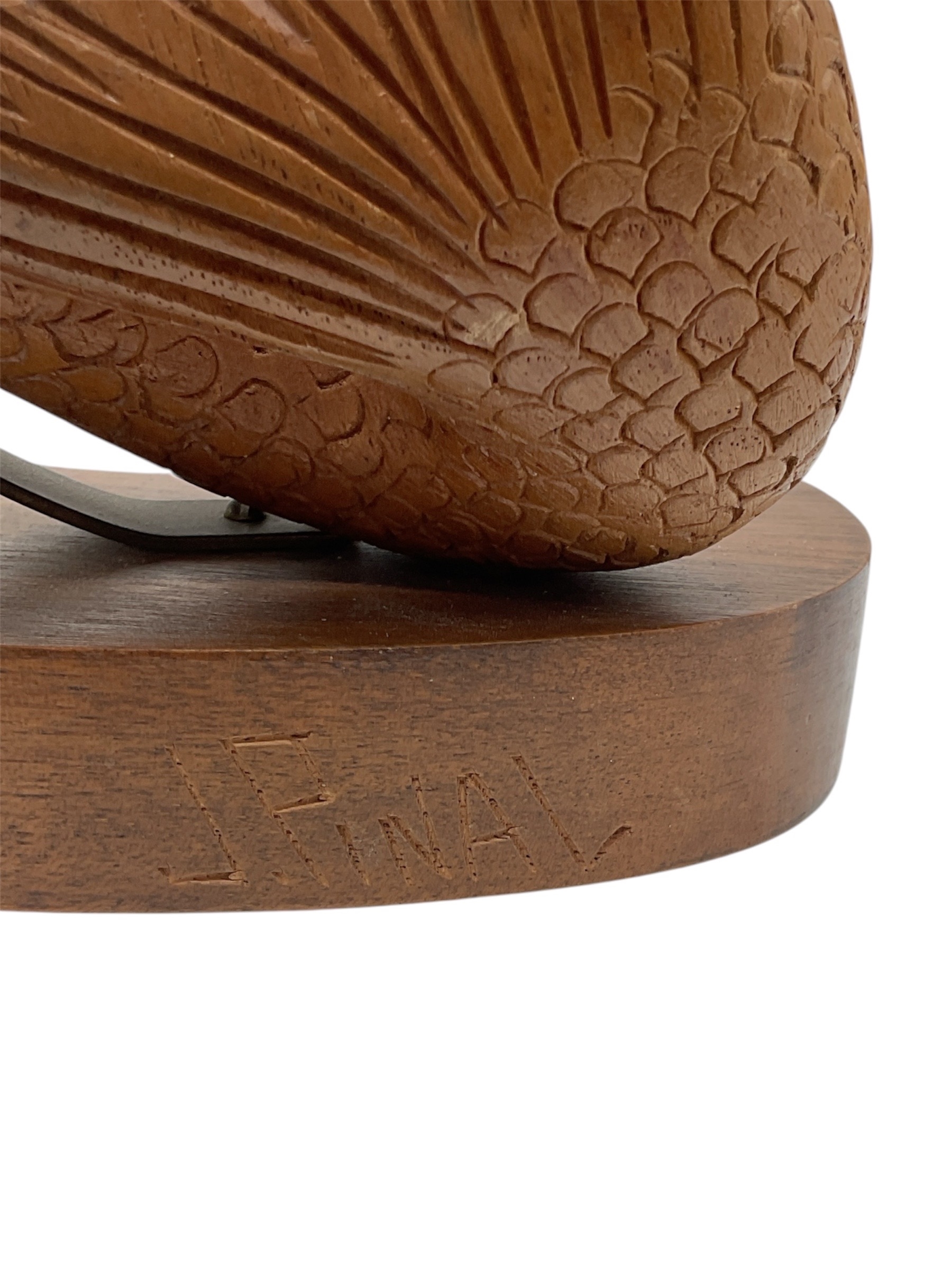 A wooden sculpture of a winged figure with an upward-reaching arm.